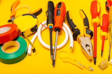 Electrician equipment on yellow background with copy space.Top view.Electrician tool set.Multimeter, tester,screwdrivers,cutters,duct tape,lamps,tape measure and wires.Flet lay. © Avocado_studio