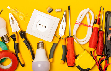Electrician equipment on yellow background with copy space.Top view.Electrician tool set.Multimeter, tester,screwdrivers,cutters,duct tape,lamps,tape measure and wires.Flet lay. © Avocado_studio