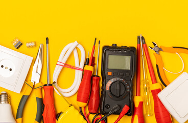 Electrician equipment on yellow background with copy space.Top view.Electrician tool set.Multimeter, tester,screwdrivers,cutters,duct tape,lamps,tape measure and wires.Flet lay. © Avocado_studio