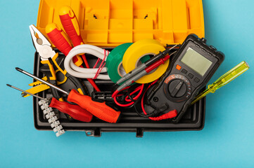 Electrician equipment on blue background with copy space.Top view.Electrician tool set.Multimeter, tester,screwdrivers,cutters,duct tape,lamps,tape measure and wires.Flet lay. © Avocado_studio