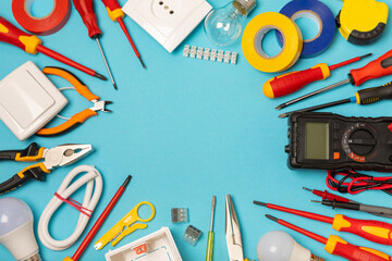 Electrician equipment on blue background with copy space.Top view.Electrician tool set.Multimeter, tester,screwdrivers,cutters,duct tape,lamps,tape measure and wires.Flet lay. © Avocado_studio
