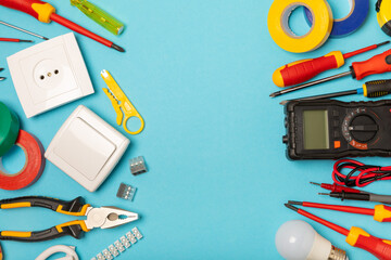 Electrician equipment on blue background with copy space.Top view.Electrician tool set.Multimeter, tester,screwdrivers,cutters,duct tape,lamps,tape measure and wires.Flet lay. © Avocado_studio
