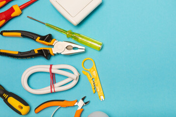 Electrician equipment on blue background with copy space.Top view.Electrician tool set.Multimeter, tester,screwdrivers,cutters,duct tape,lamps,tape measure and wires.Flet lay. © Avocado_studio