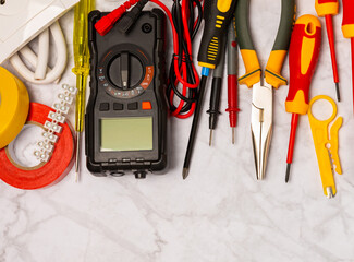 Electrician equipment on marble background with copy space.Top view.Electrician tool set.Multimeter, tester,screwdrivers,cutters,duct tape,lamps,tape measure and wires.Flet lay. © Avocado_studio