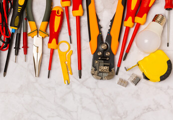 Electrician equipment on marble background with copy space.Top view.Electrician tool set.Multimeter, tester,screwdrivers,cutters,duct tape,lamps,tape measure and wires.Flet lay. © Avocado_studio
