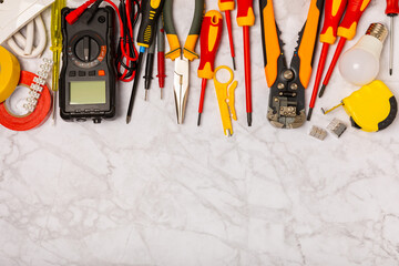 Electrician equipment on marble background with copy space.Top view.Electrician tool set.Multimeter, tester,screwdrivers,cutters,duct tape,lamps,tape measure and wires.Flet lay. © Avocado_studio