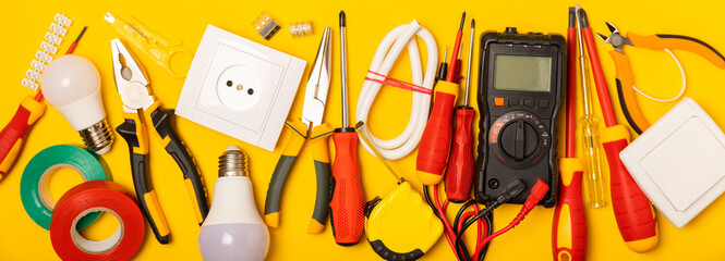 Electrician equipment on yellow background with copy space.Top view.Electrician tool set.Multimeter, tester,screwdrivers,cutters,duct tape,lamps,tape measure and wires.Flet lay. © Avocado_studio