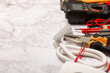 Electrician equipment on marble background with copy space.Top view.Electrician tool set.Multimeter, tester,screwdrivers,cutters,duct tape,lamps,tape measure and wires.Flet lay. © Avocado_studio