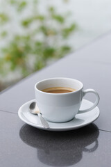A white cup of coffee is placed on the table by the sea.