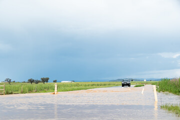 Car on road approaching floodwater with water depth indicator