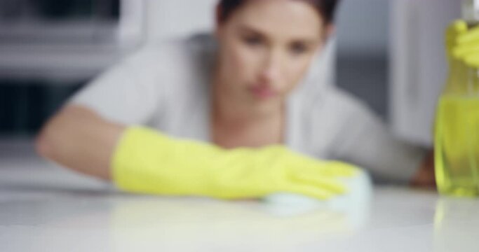 Housekeeping, detergent and woman cleaning a countertop with a sponge in the kitchen at home. Female maid, cleaner or housewife wipe the table for dirt, bacteria or dust with sanitizing spray bottle.