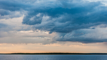 Naklejka na ściany i meble Dramatic clouds on a summer evening by the Porttipahta reservoir in Finnish Lapland