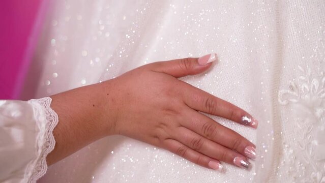La Mano de una Mujer Embellece un Vestido de Boda con sus Elegantes U&ntilde;as - Descubre la Armon&iacute;a entre las U&ntilde;as y el Vestido de Boda - mano de mujer con arreglo de u&ntilde;as desliz&aacute;ndose por un vestido 