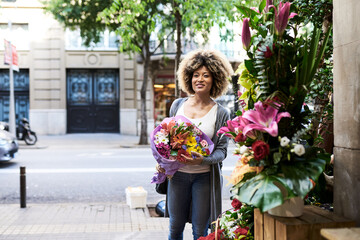 Smiling ethnic woman with bouquet of flowers
