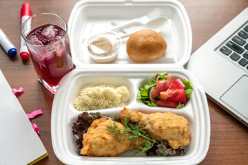 Meatball bento in the plastic box with the ultrabook on background. Busy lunch