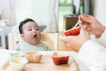Obraz na płótnie Canvas パパに離乳食を食べさせてもらいたくて口を開けて待っている生後8か月の赤ちゃん