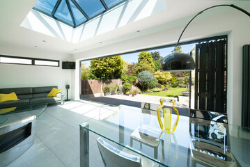 View from interior of designer, lifestyle, open-plan room through open bifold doors to beautiful...