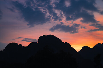 Obraz premium Mountain as the sun sets. Mountain peak green nature scenery. Beautiful sunset over the mountain range at vang vieng.