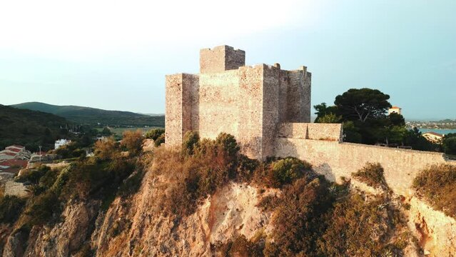 Spiaggia di Bagno delle Donne vista dalla rocca al tramonto. Borgo antico sul mare in Toscana.