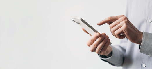 Young man texting on smartphone over gray background. Close up of adult male hand using mobile phone, panoramic banner with copyspace - 609051047