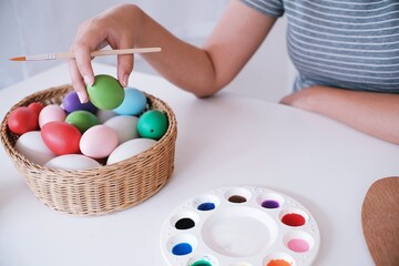 Fototapeta na wymiar Woman painting Easter eggs at home. family preparing for Easter. Hands of a girl with a easter egg