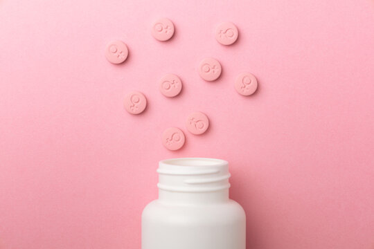 Female gender symbol on pink pills. Pills for women. Contraceptives or menstrual days. jar with pills. Top view