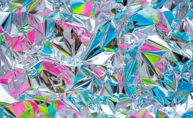 The surface of the crumpled foil is highlighted in different colors. Background holographic...