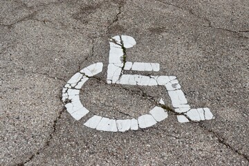 A close view of the white handicap sign on the pavement.