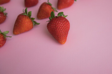 Ripe strawberries lie on a pink background. View from above.