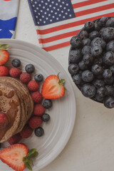 Pancakes with forest fruits berries on beautiful table. Healthy breakfast. Blueberries, raspberries and strawberry on pancakes. Independence Day 4th of July. 