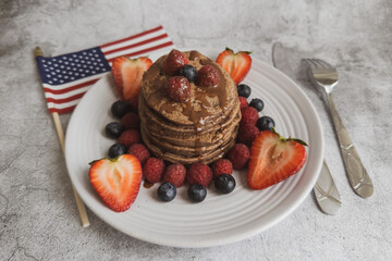 Pancakes with forest fruits berries on beautiful table. Healthy breakfast. Blueberries, raspberries and strawberry on pancakes. Independence Day 4th of July. 
