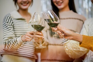 Cheerful friends enjoying home Birthday holiday party. Asian Friends cheering drinking red wine celebrating Christmas or New Year party