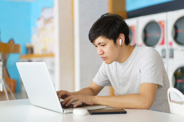 Asian man using laptop or notebook computer for online video conference and entertainment while...