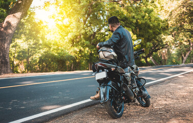 Fototapeta na wymiar Biker sitting on his motorcycle at the side of the road. Man sitting on his motorcycle at the side of the road