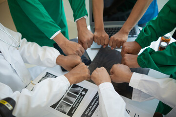 The medical team joins hands after the meeting and discusses the treatment of severely ill patients...