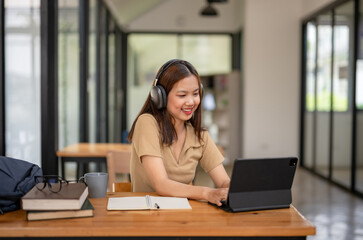 Fototapeta premium Happy female student focus on studying online on laptop, typing on laptop. Remote education and e-learning, Video call and research.