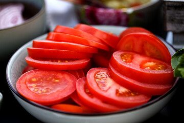 Fototapeta Sliced tomatoes laying in the bowl. Red tomato ready to eat. obraz