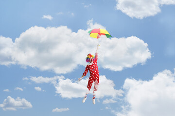 Funny clown holding an umbrella and flying up