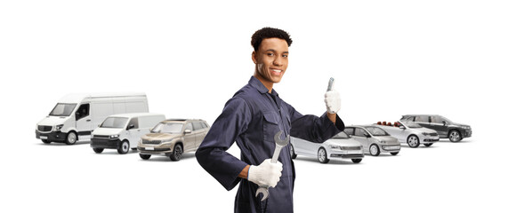 African american car mechanic holding a wrench and gesturing thumbs up in front of vehicles