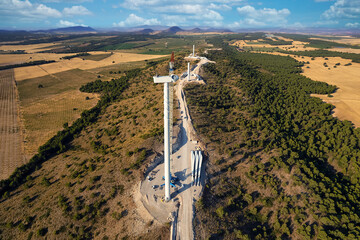 View from above of the Installation of a wind turbine farm. Team of workers and engineers with a giant crane installing a nacelle in a wind turbine on a windmill farm, Spain - obrazy, fototapety, plakaty