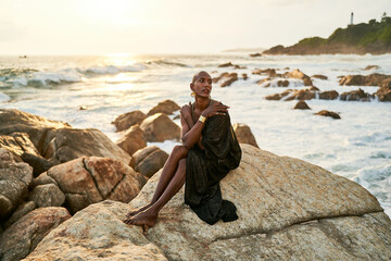 Epatage lgbtq black man poses on scenic ocean beach looks at camera demonstrates jewellery ....