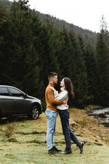 couple outdoors in the autumn season. lovers walk in a mountainous area near the river and forest. pastime of lovers during travel