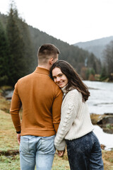 Fototapeta premium couple outdoors in the autumn season. lovers walk in a mountainous area near the river and forest. pastime of lovers during travel