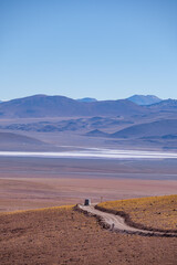 Fototapeta na wymiar Vertical view of a campervan on an off road road with a salt flat behind in the Bolivian Andes