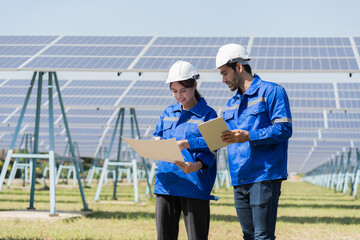Male and female engineer worker working in solar panels power farm. Two technician working at solar...