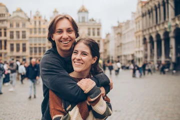 Tuinposter couple standing and hugging in front of a crowded city center in europe grand palace © kristineldridge