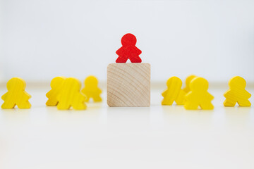 Wooden figure standing on a cube higher than others - concept of leadership or hierarchy