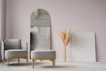 Classic modern grey armchairs, ottoman, mirror, pampas grass dried flowers in a vase in the living room interior