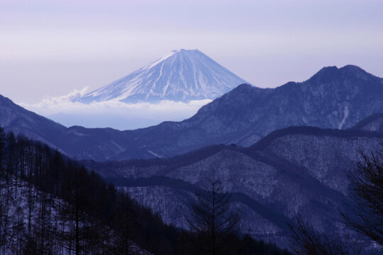 mount fuji in winter with layers of mountains in the foreground