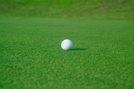 Golf ball with shadow on flat green